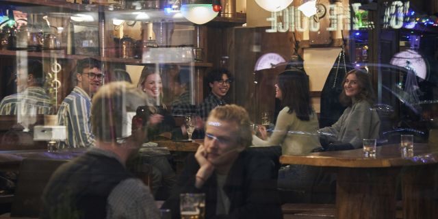 FILE - People sit in a bar in Stockholm, Sweden, Wednesday, March 25, 2020. The streets of Stockholm are quiet but not deserted. People still sit at outdoor cafes in the center of Sweden's capital. Vendors still sell flowers. Teenagers still chat in groups in parks. Some still greet each other with hugs and handshakes. After a long, dark Scandinavian winter, the coronavirus pandemic is not keeping Swedes at home even while citizens in many parts of the world are sheltering in place and won't find shops or restaurants open on the few occasions they are permitted to venture out. (AP Photo/David Keyton, File)